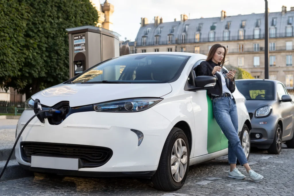 A girl with her white car with EV charger plugged in