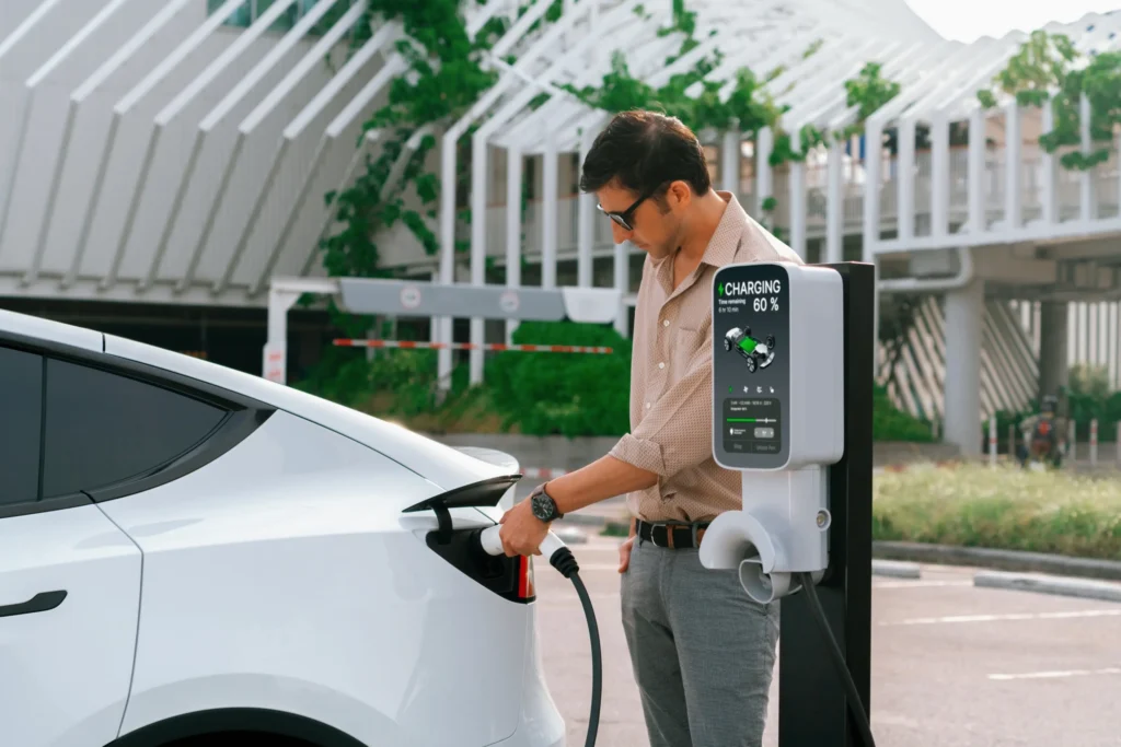 Man Charging the car with EV Charger in a day light